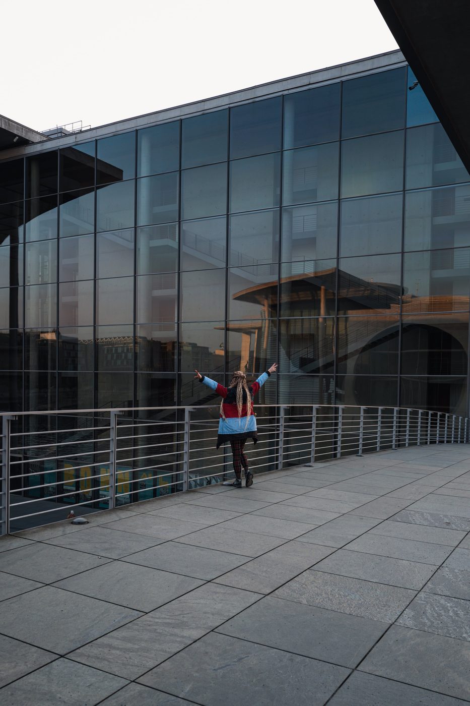 Woman with arms raised on an overhanging glass terrace, Berlin