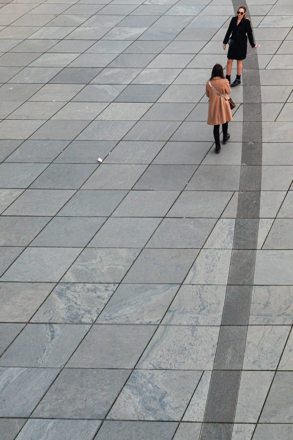 High-angle view of two women crossing a vast paved esplanade, Berlin