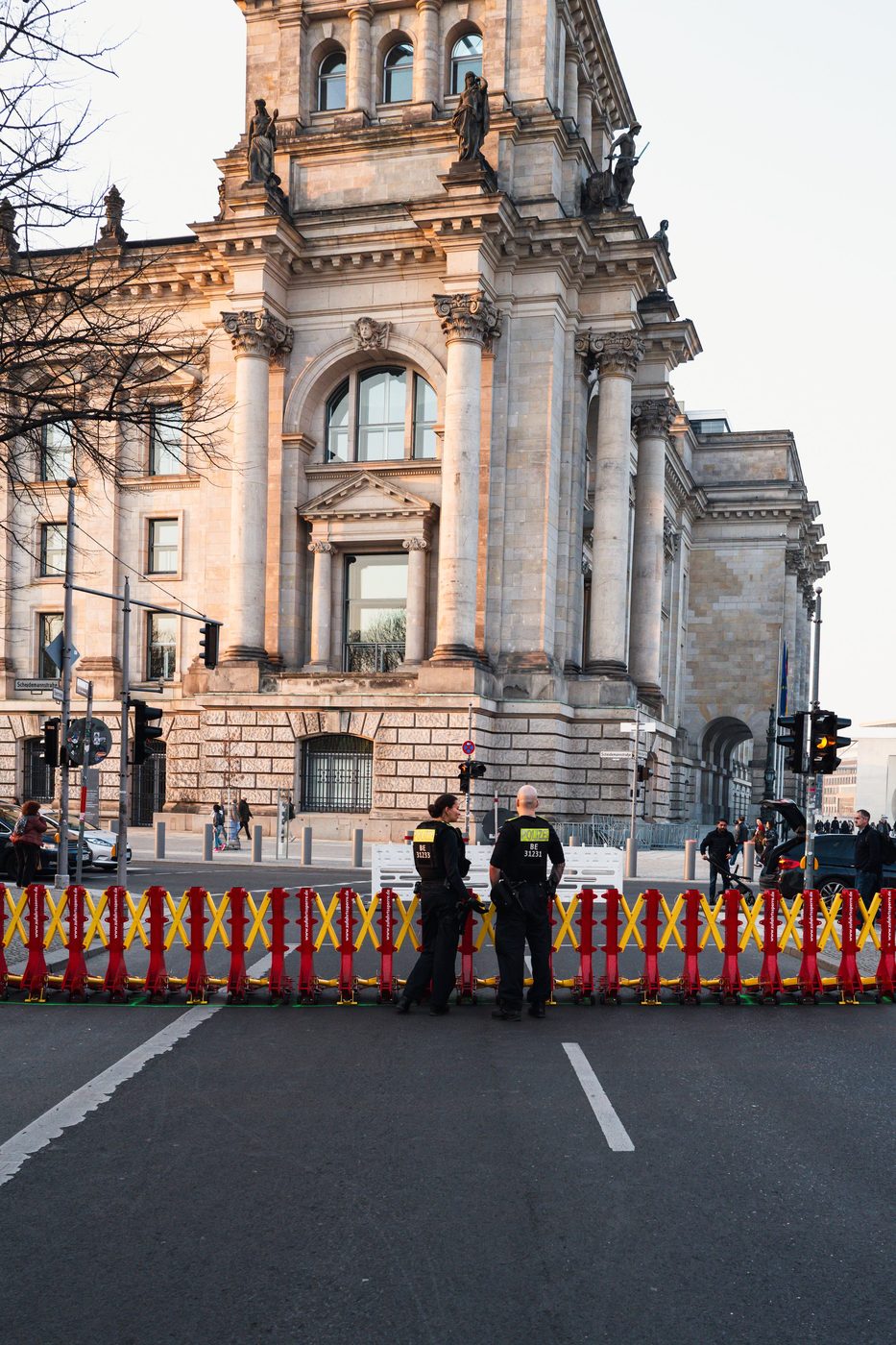 Two police officers stationed behind a red and yellow barrier in front of the Reichstag, Berlin