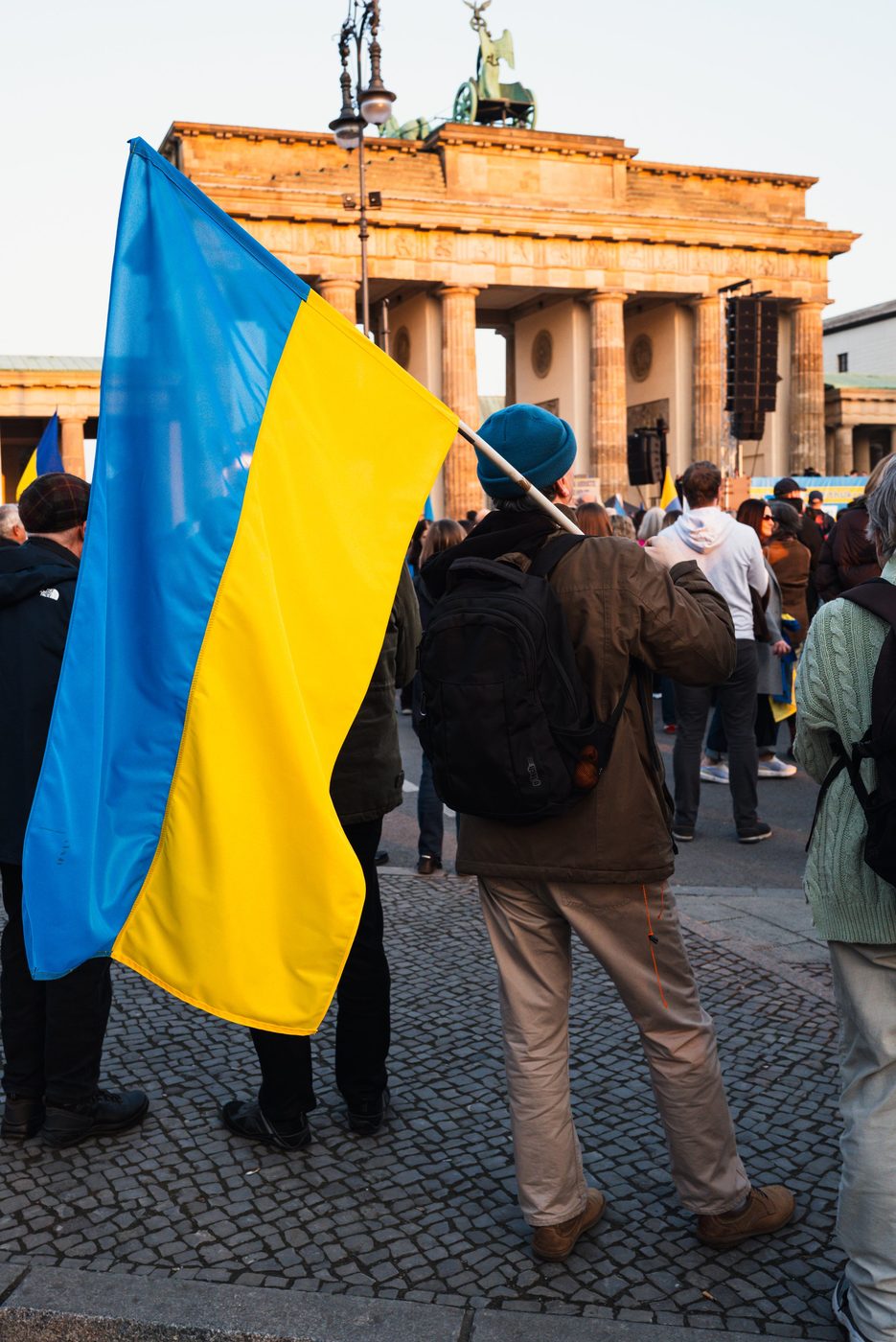 Man carrying a Ukrainian flag in front of the Brandenburg Gate, Berlin