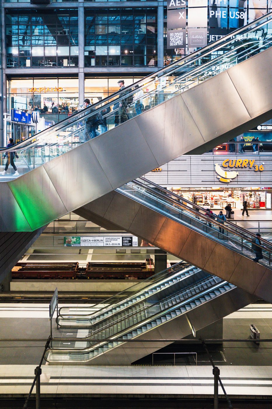 Crisscrossing escalators leading toward the station's shops and signs, Berlin
