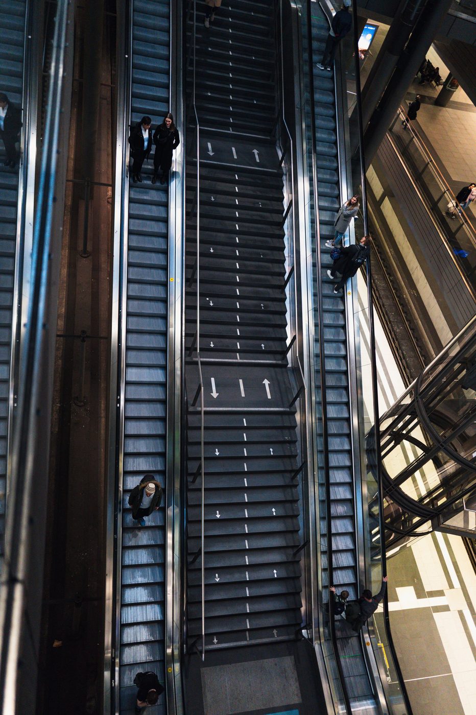 Diagonal high-angle view of crisscrossing escalators and their passengers, Berlin