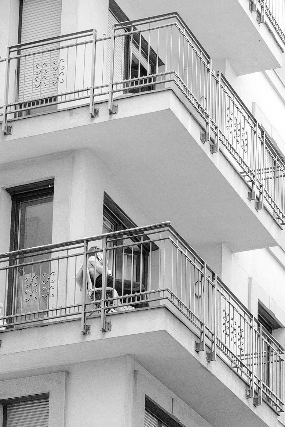 A woman sitting alone on a cantilevered balcony, Budapest