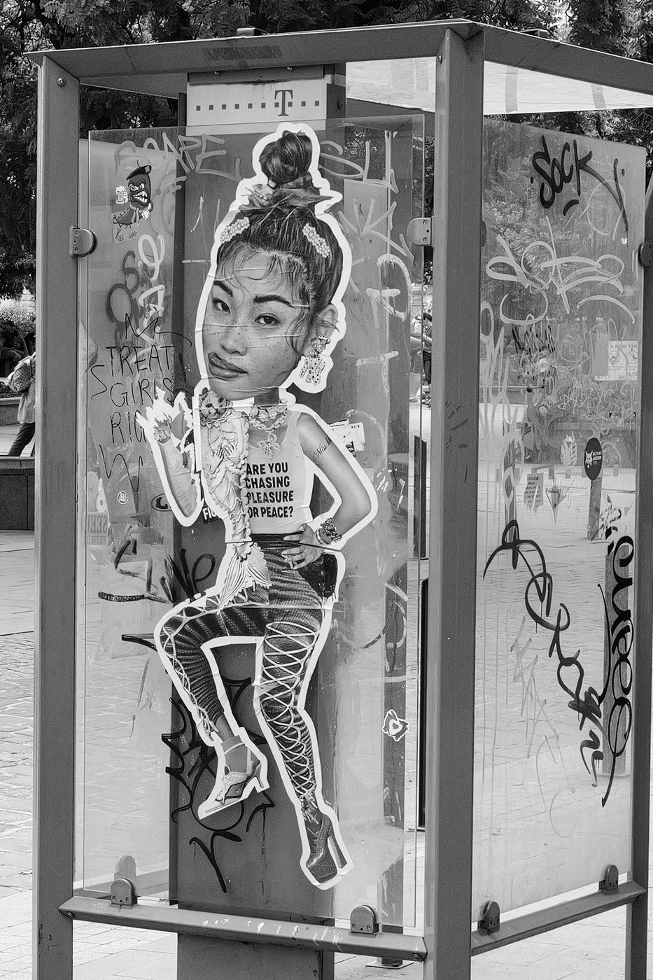 Sticker of a stylised woman on a phone booth covered in graffiti, Budapest