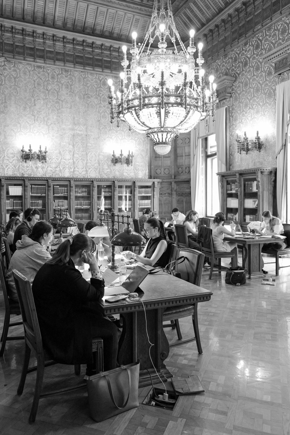 Students at work under an immense library chandelier, Budapest