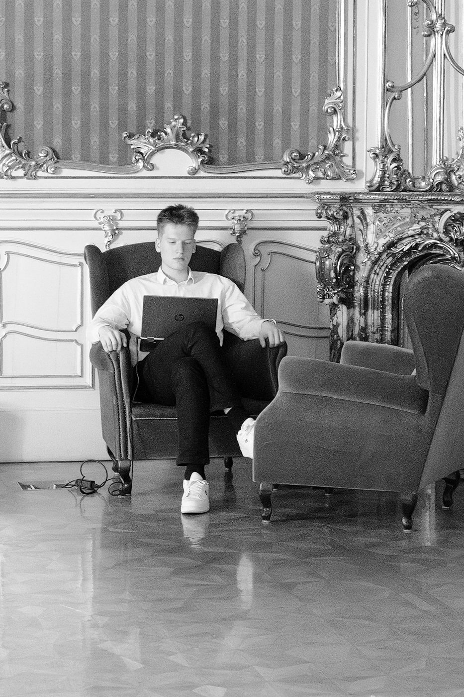 A young man working on his computer in a gilded armchair, Budapest