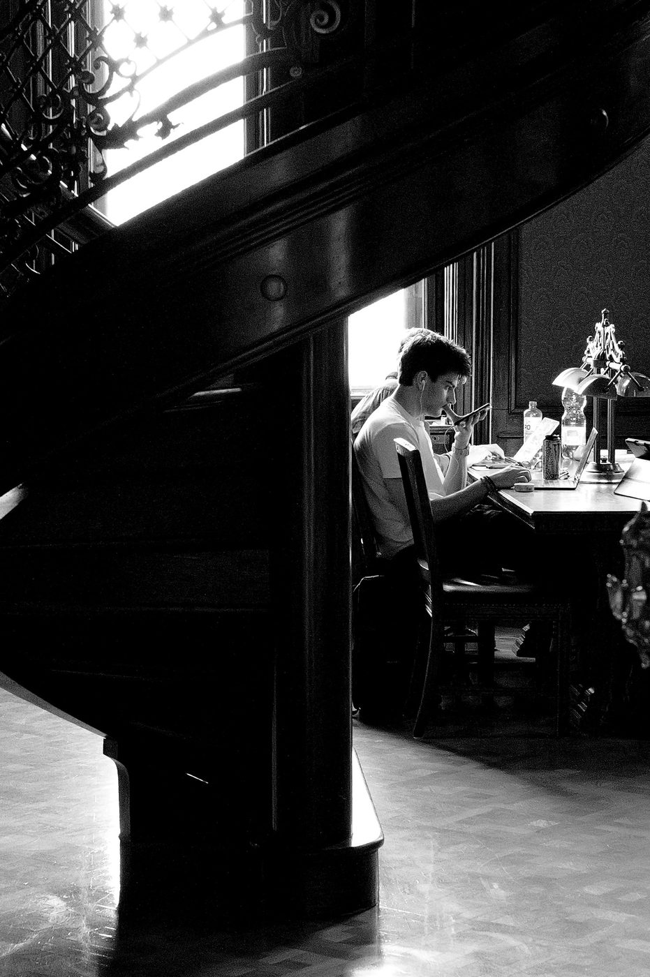 A student on the phone near a spiral staircase, Budapest