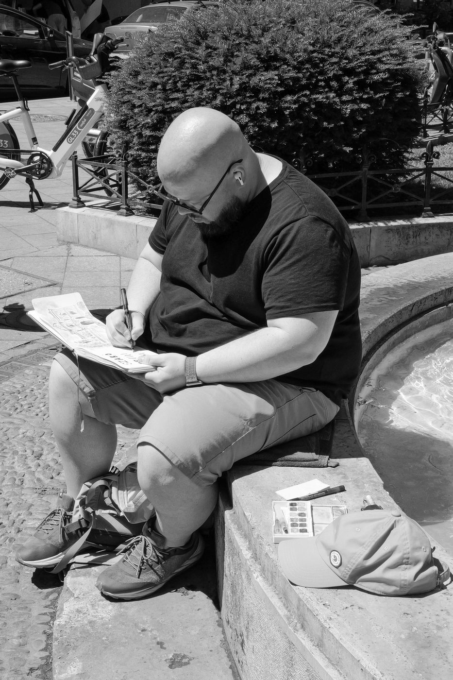 An artist sketching in a notebook by a fountain, Budapest
