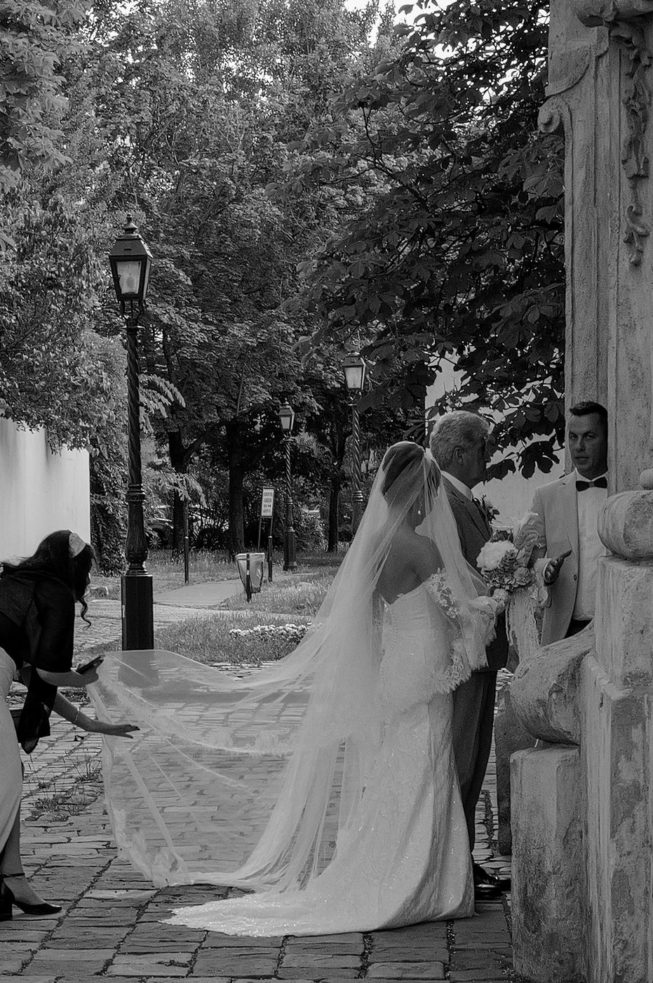 Bridal gown train lifted by a bridesmaid in a pathway, Budapest