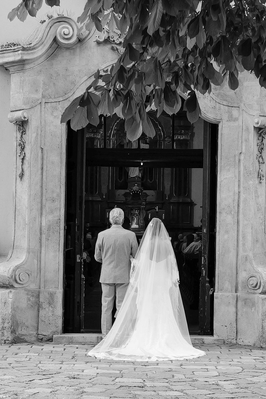 Bride and groom seen from behind facing a church gate, Budapest