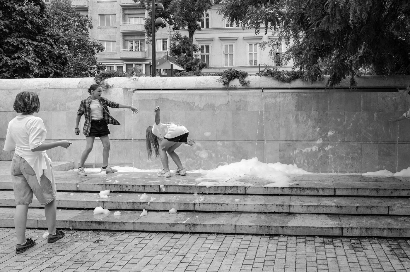 Children splashing foam in an urban fountain, Budapest