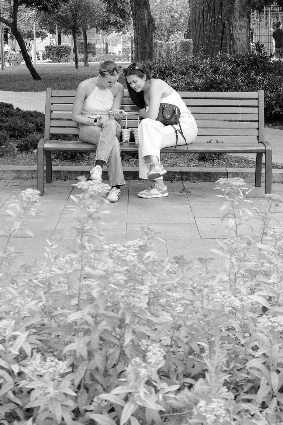 Two friends sitting on a bench looking at a phone, Budapest
