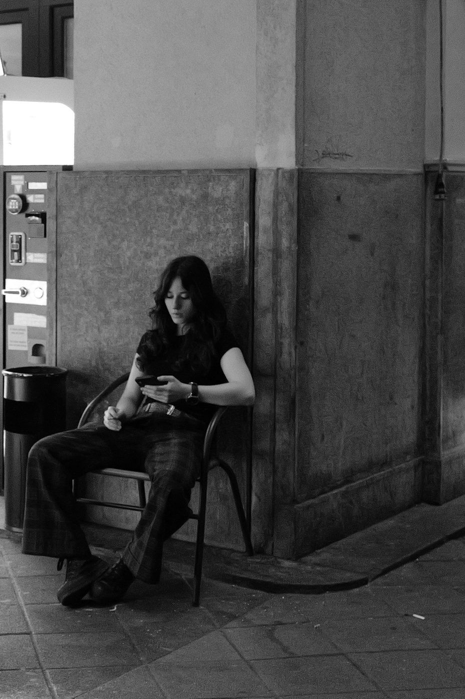 A woman on the phone sitting alone against a station wall, Budapest