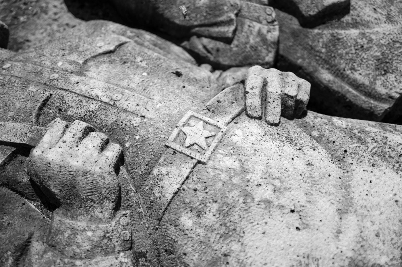 Sculpted detail of hands and a star badge on a statue, Budapest