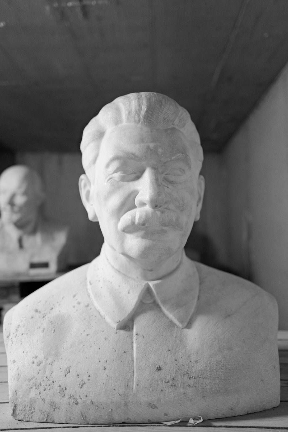 Plaster bust of a mustached leader, another bust blurred in the background, Budapest