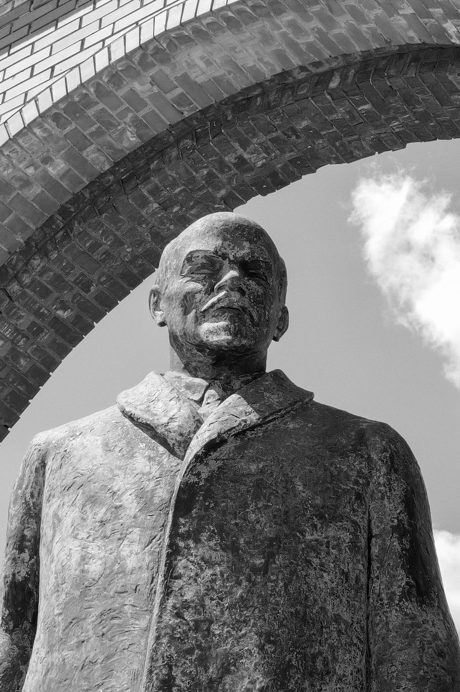 Bronze statue of a bald man under a brick arch, Budapest