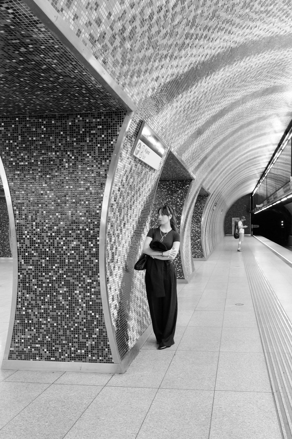 A woman waiting against a mosaic pillar in a metro station, Budapest