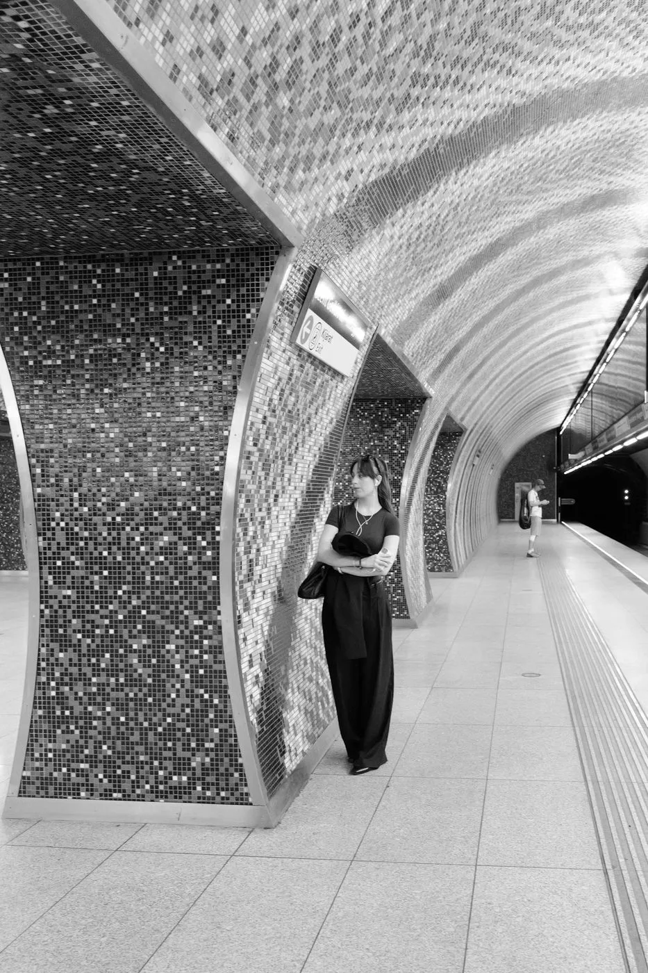 Une passante attendant contre un pilier de mosaique dans une station de metro, Budapest