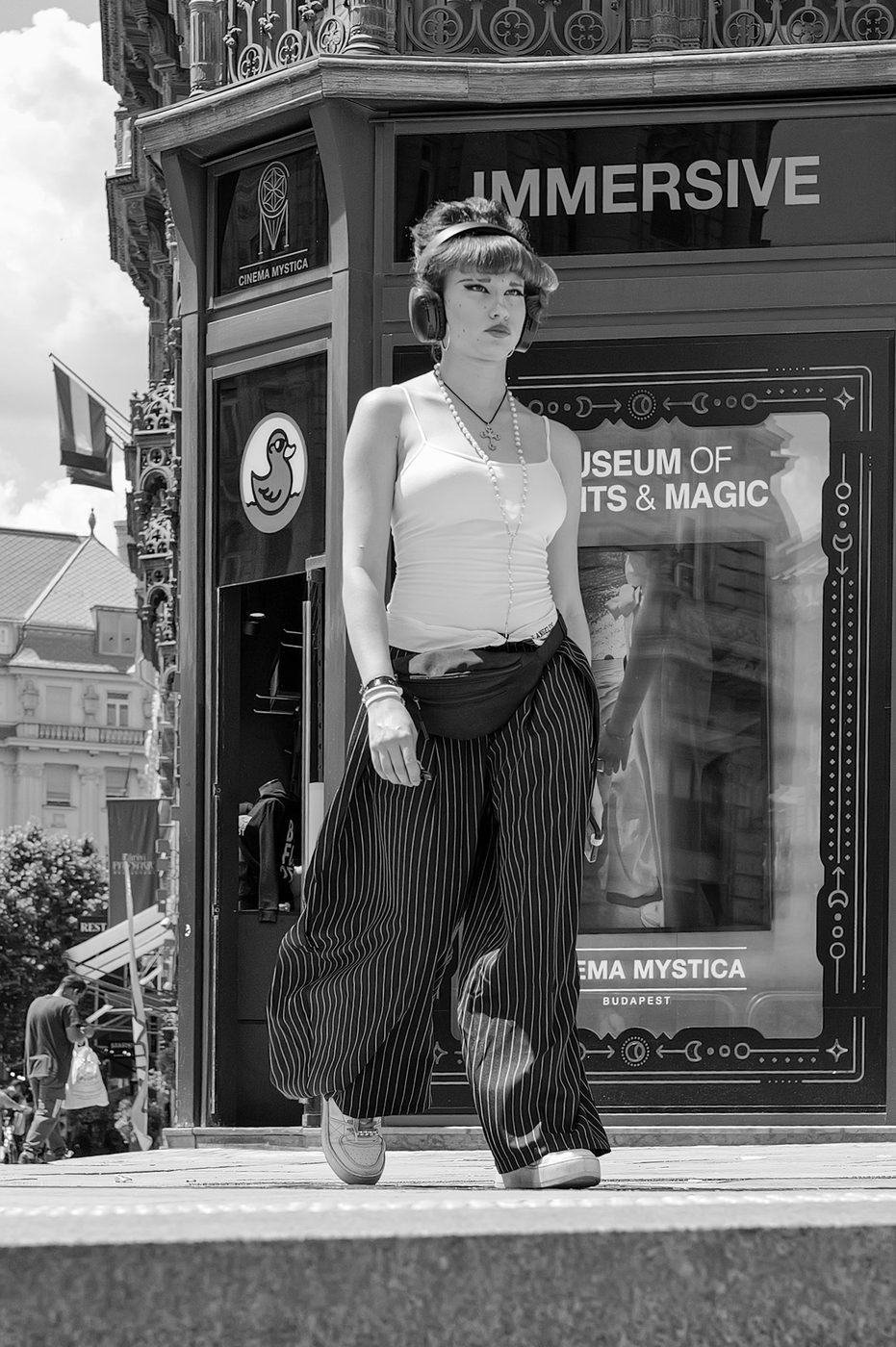 A woman with headphones on in front of an immersive cinema window, Budapest