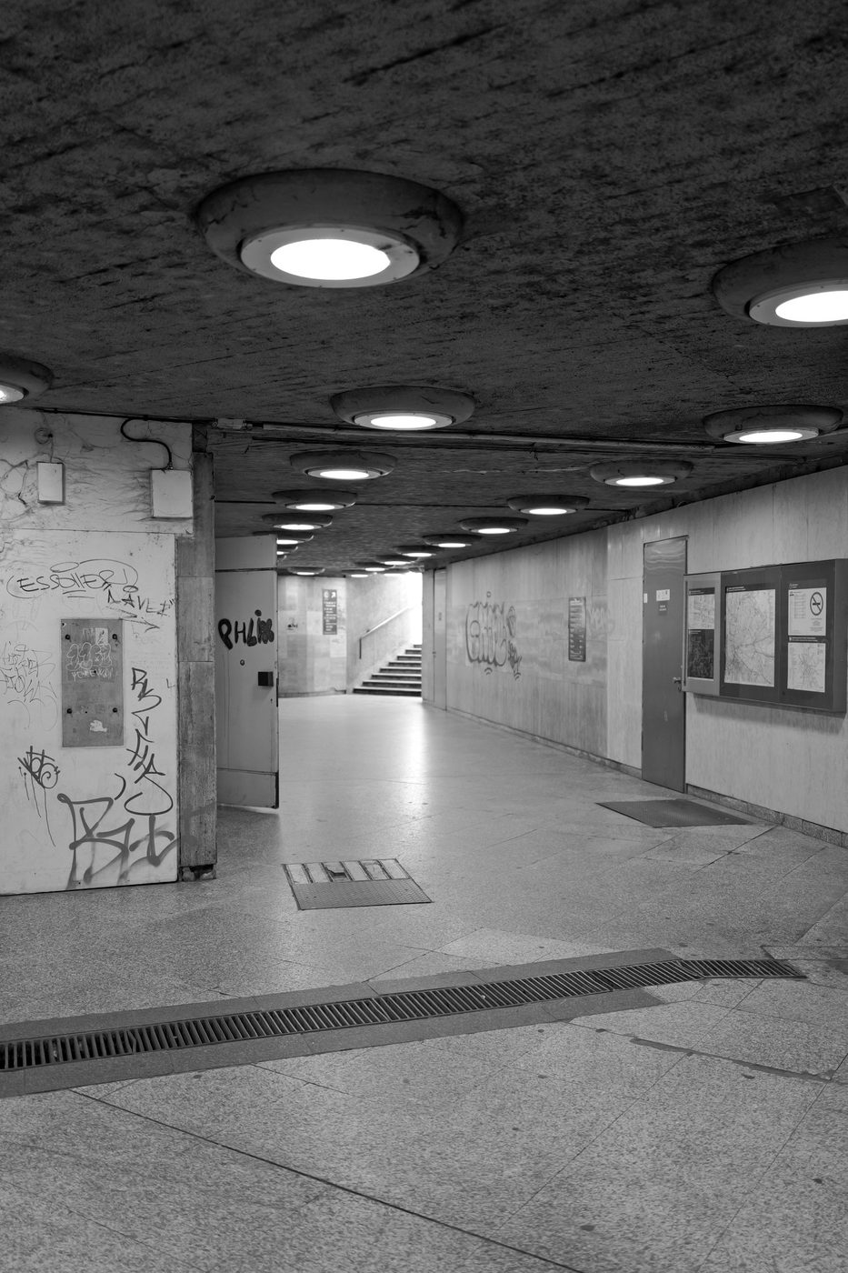 Empty underground corridor with round ceiling lights and tagged walls, Budapest