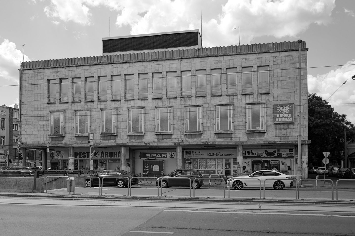 Facade of a socialist-era department store with shop signs on the ground floor, Budapest