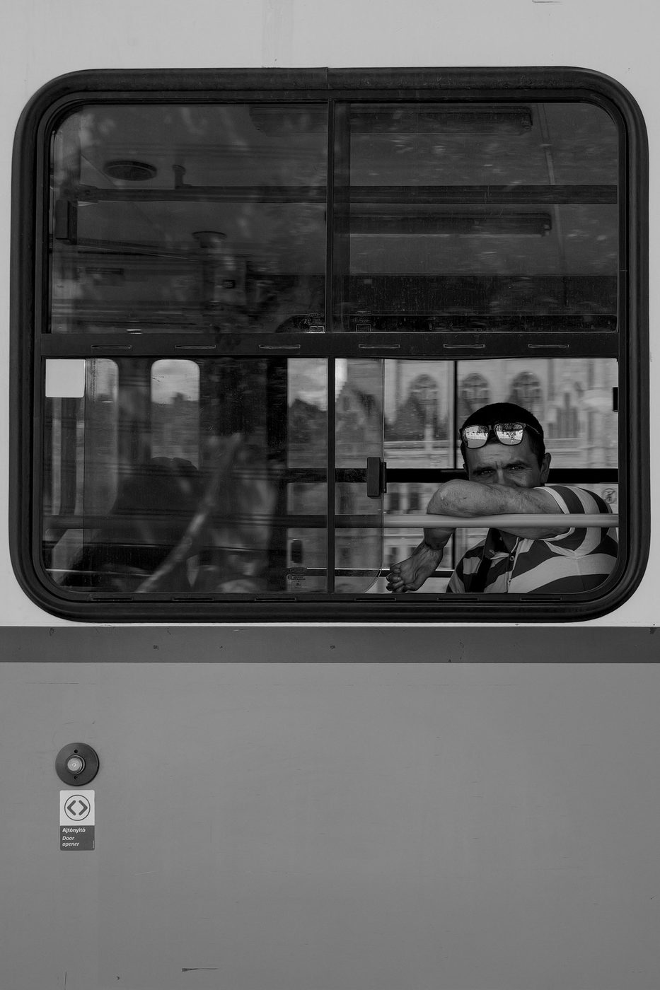 Portrait of a passenger leaning on a tram window, glasses on his head, Budapest