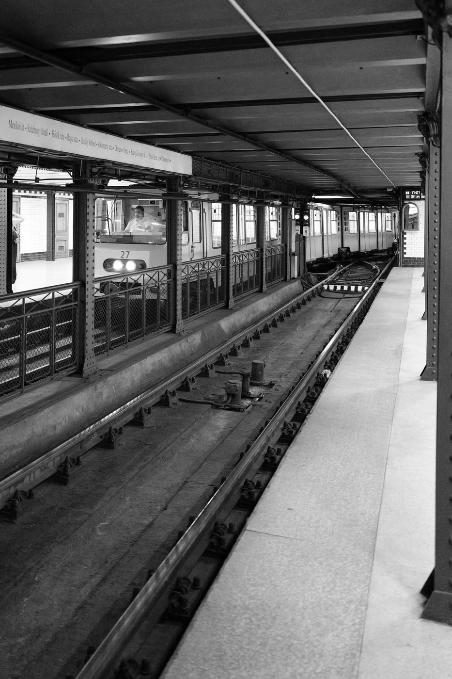 A historic metro train entering the station, driver visible, Budapest