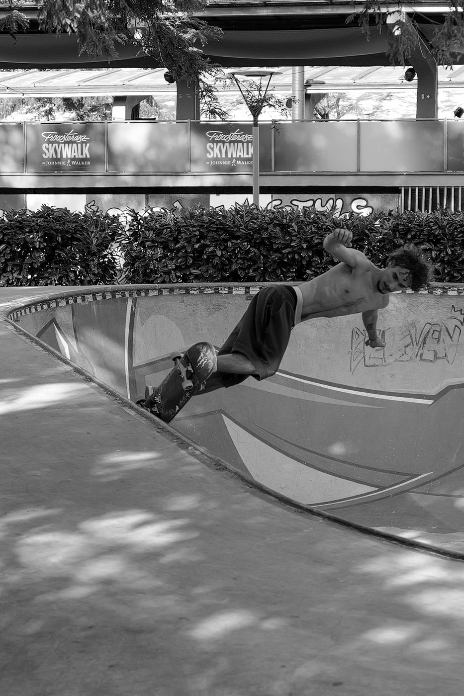 A shirtless skater performing a trick at the edge of a bowl, Budapest