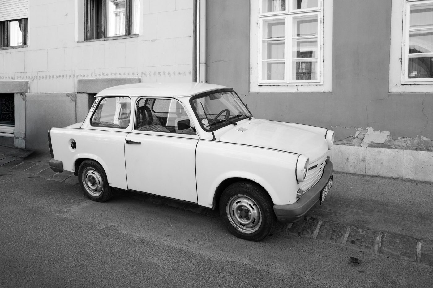 An old white Trabant parked in front of a peeling facade, Budapest