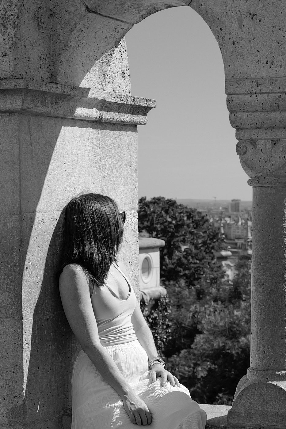 A woman in a white dress leaning against a pillar of the Bastion, Budapest