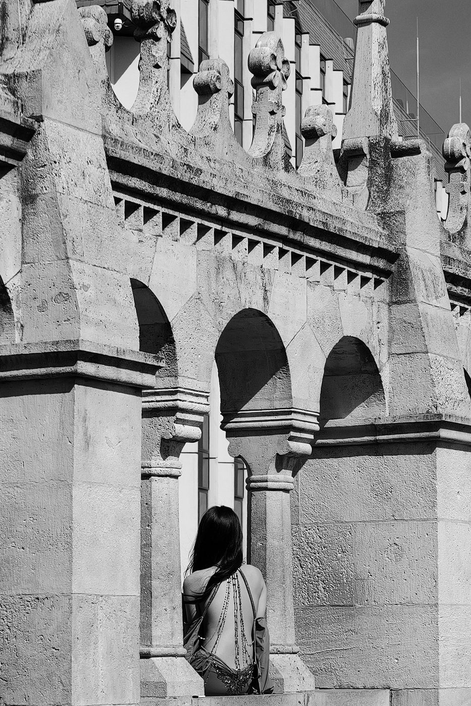 A woman seen from behind between two carved arches of a Gothic building, Budapest