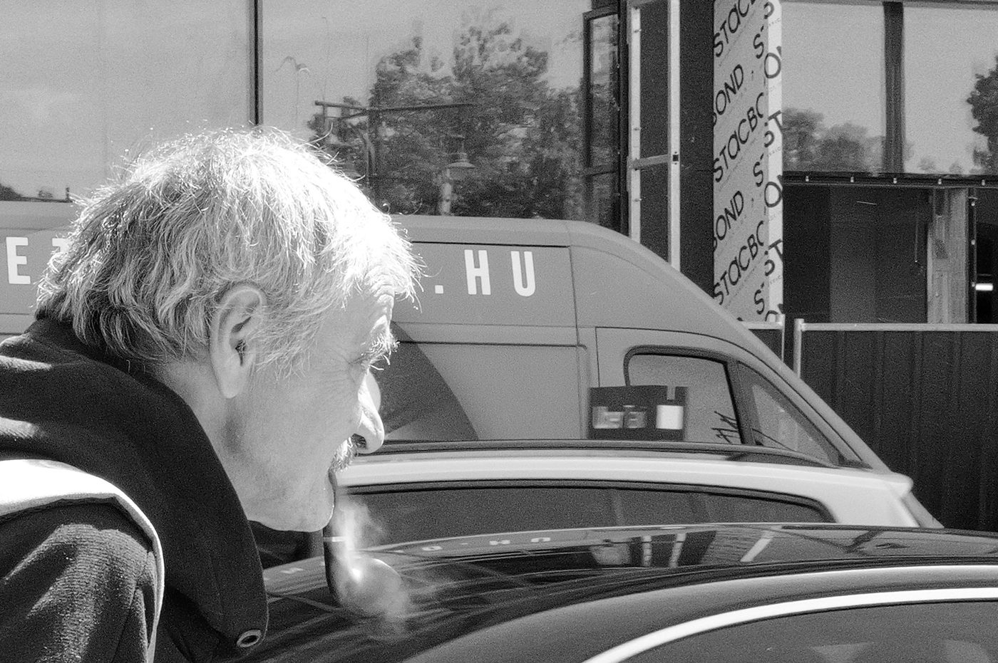 Profile portrait of an elderly man smoking a pipe near a car, Budapest