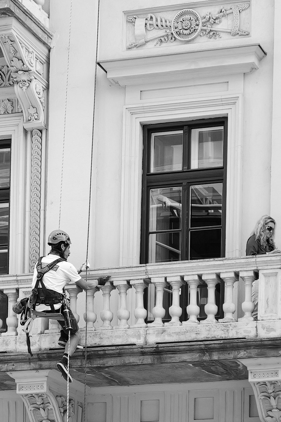 A rope-access technician working on the ornate balcony of an old building, Budapest