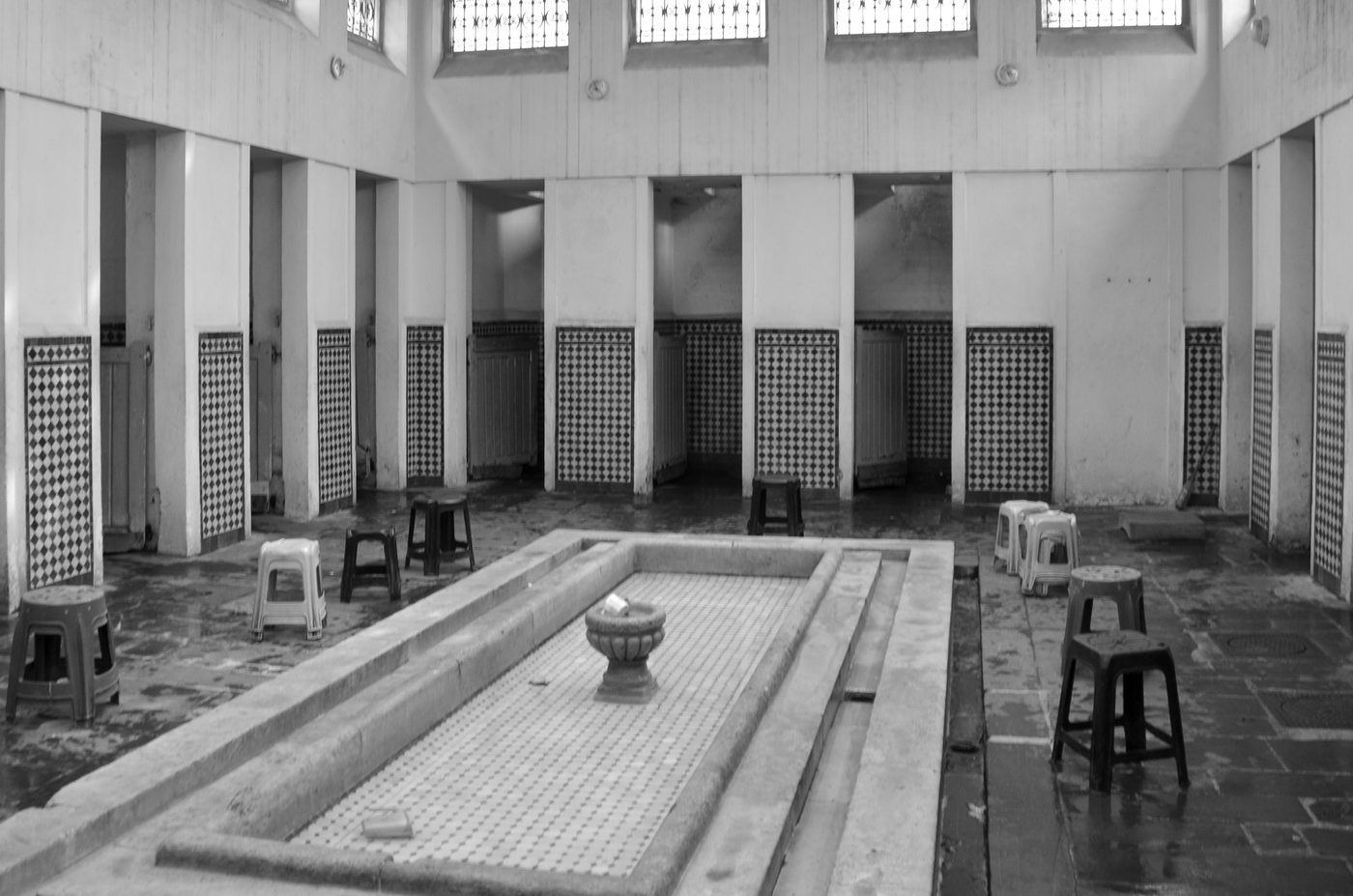 Tiled basin and stools lined up in an empty hammam, Casablanca