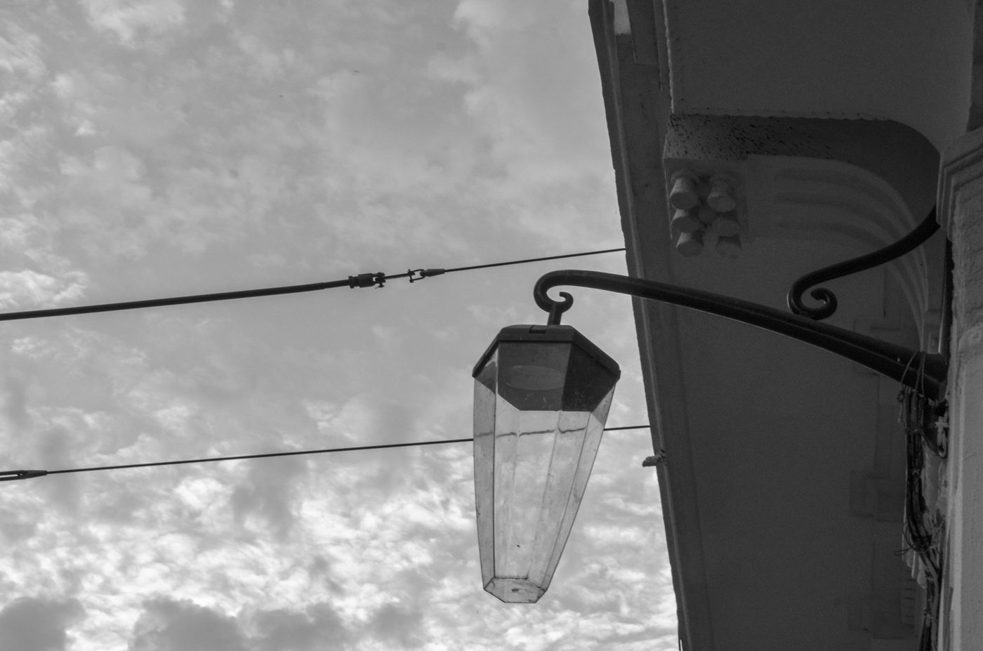 Streetlamp hanging from a wrought iron bracket, cloudy sky, Casablanca