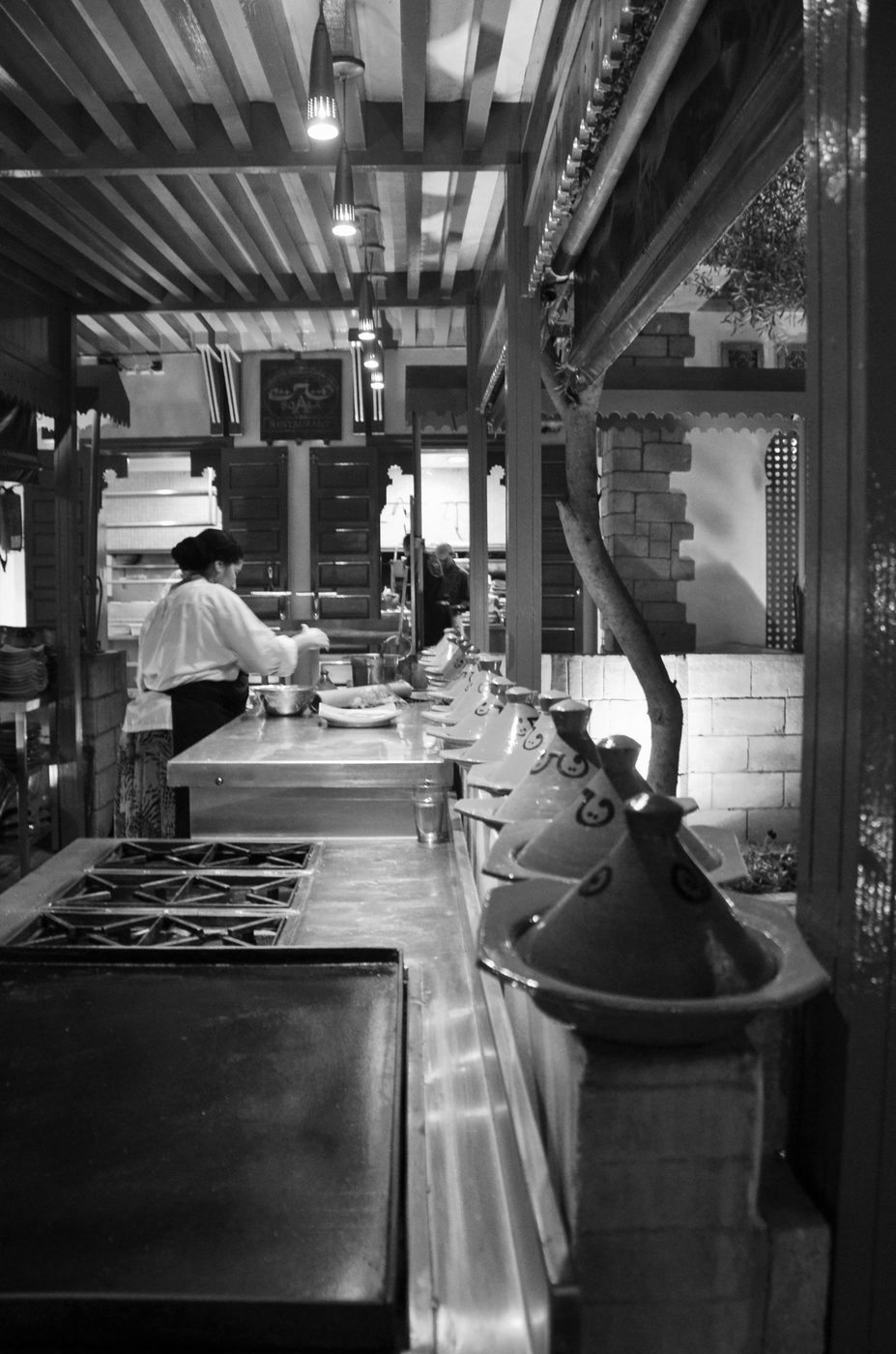 Tagines lined up near a tree in an open-air kitchen, Casablanca