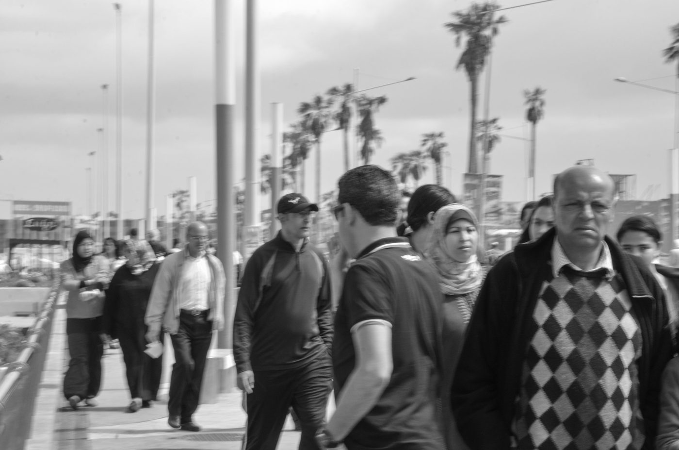 Passersby crossing paths on the palm-lined corniche, Casablanca