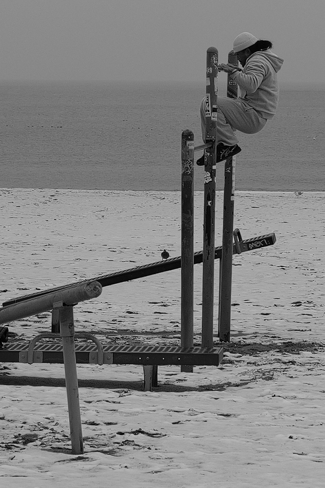 Man doing pull-ups on sports bars facing the sea, Coney Island