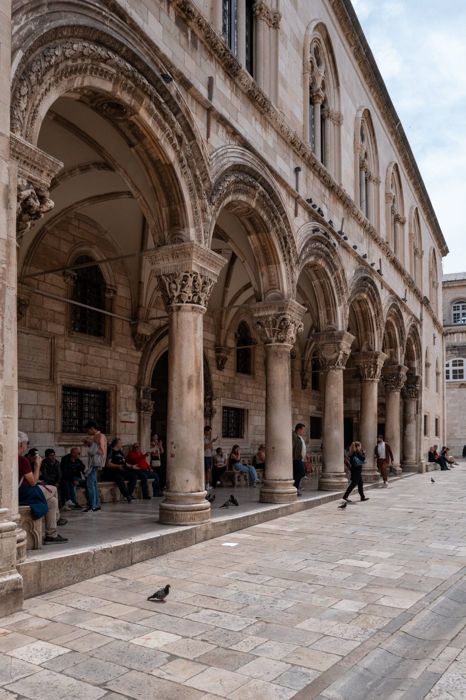 Sculpted colonnade of the Rector's Palace bustling with passers-by and pigeons, Dubrovnik