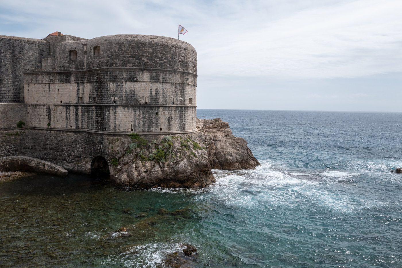 Circular bastion of the ramparts flanked by a rock battered by waves, Dubrovnik