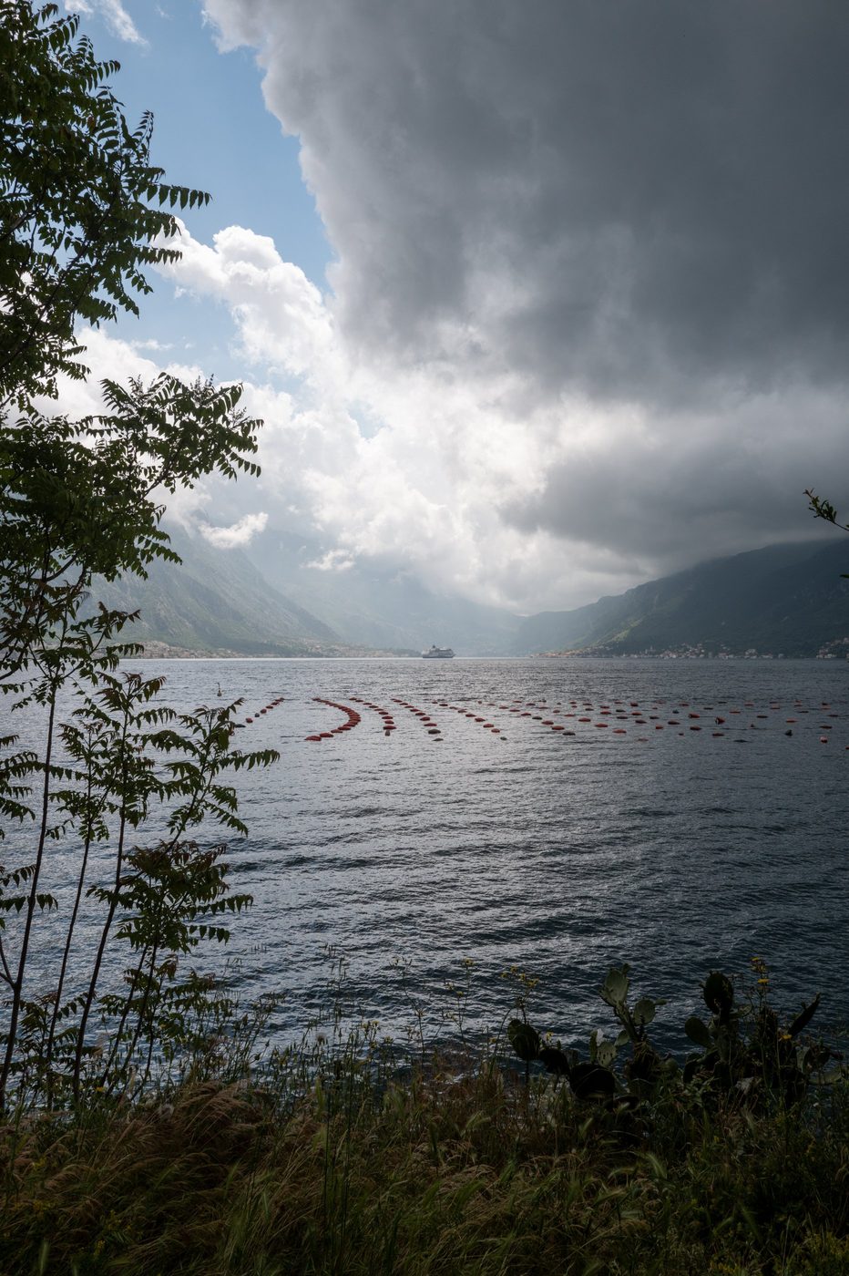 Floating fish farm in front of a cruise ship gliding under a stormy sky, Dubrovnik