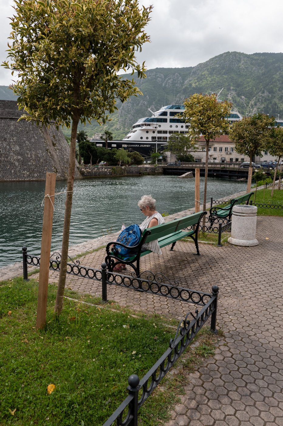 Woman reading on a bench facing the canal and the moored cruise ship, Dubrovnik