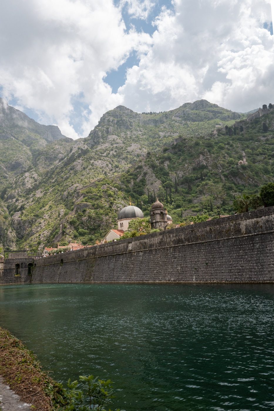 Stone ramparts lining an emerald canal beneath rocky peaks, Dubrovnik