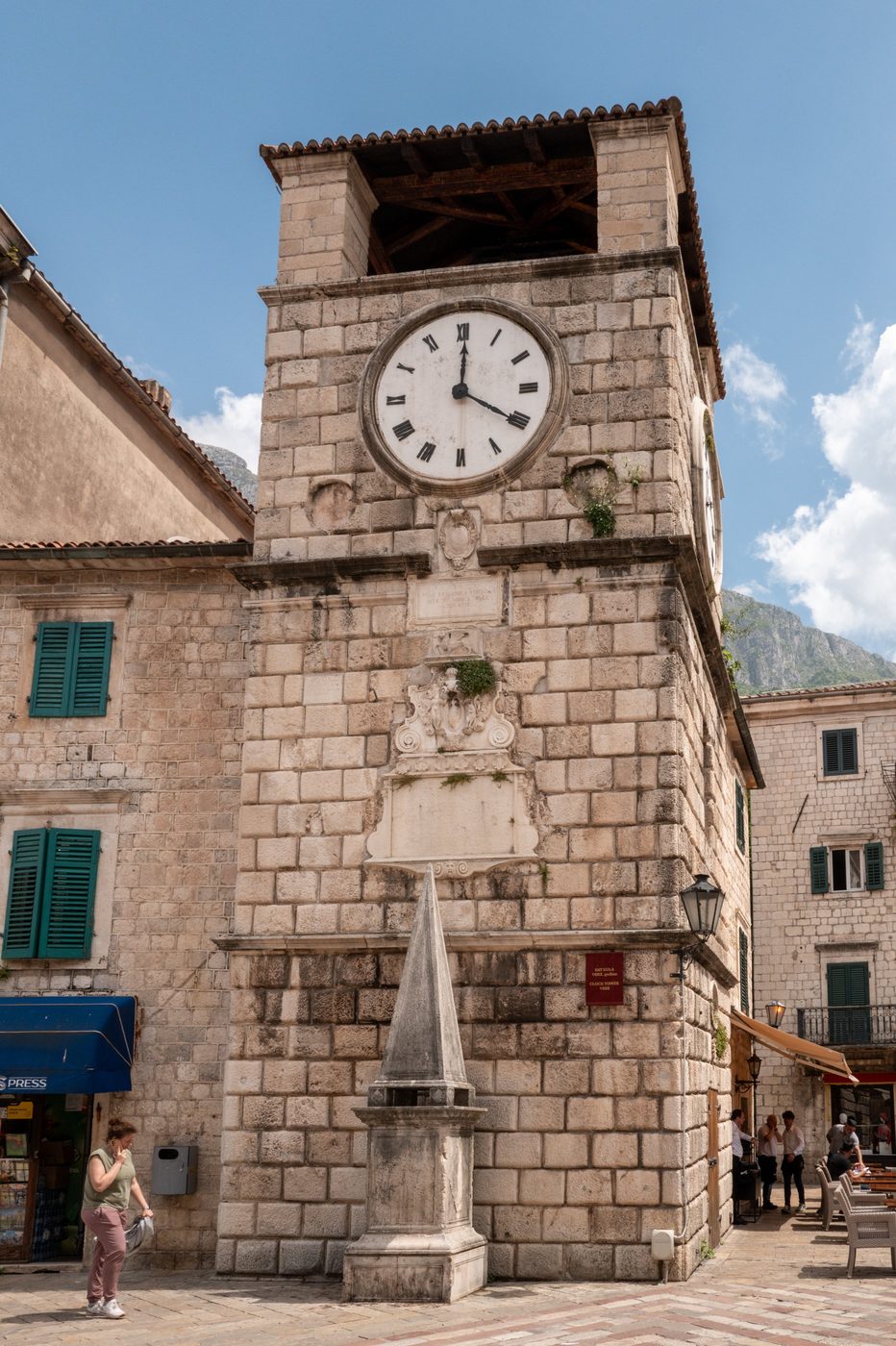 Stone clock tower with a round dial, bustling square, Dubrovnik