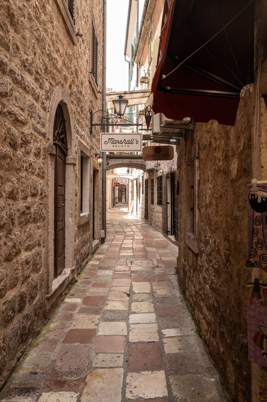 Narrow alley with hanging signs and a red awning, Dubrovnik