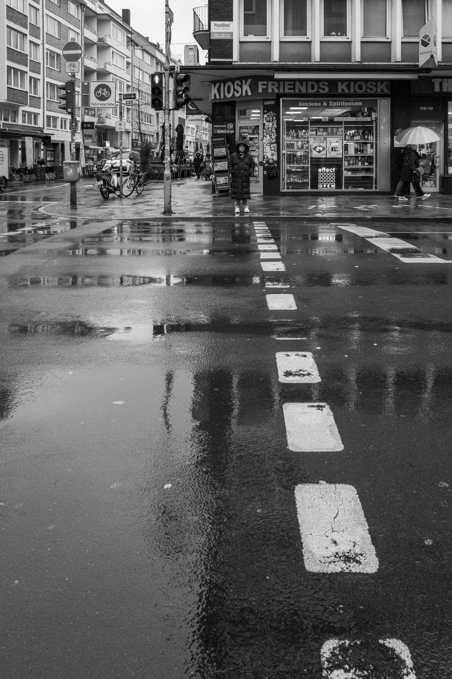 A woman waiting in front of a kiosk in the rain, Düsseldorf