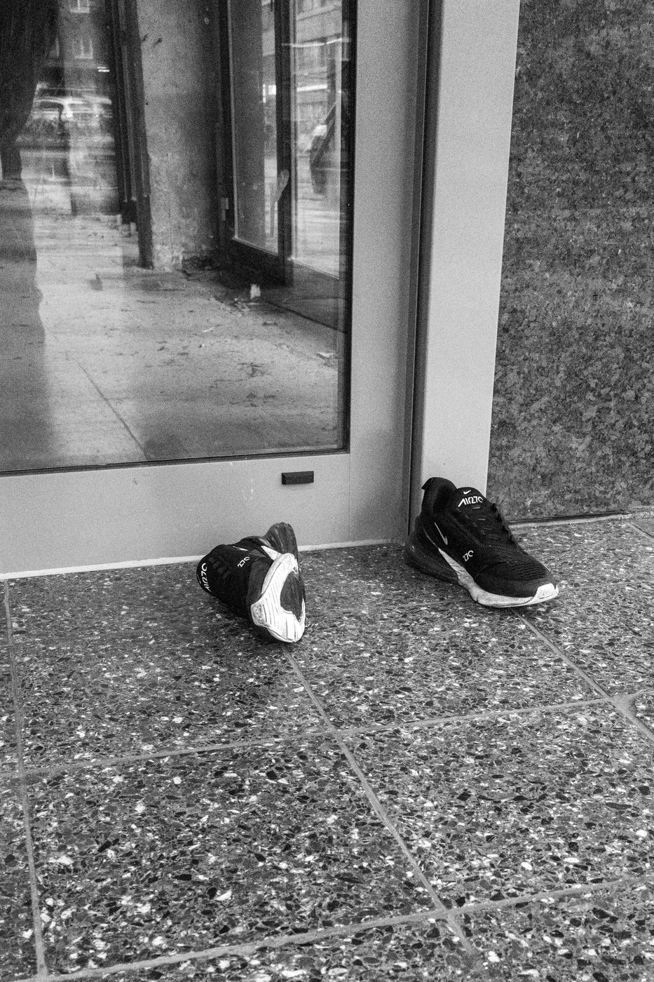 Two black sneakers abandoned in front of a shop window, Düsseldorf