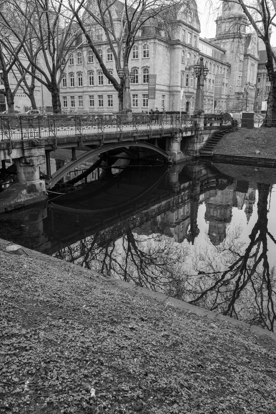 Reflection of a stone bridge and buildings in calm water, Düsseldorf