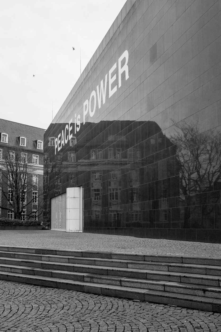 'Peace is Power' slogan written on the dark facade of a museum, Düsseldorf