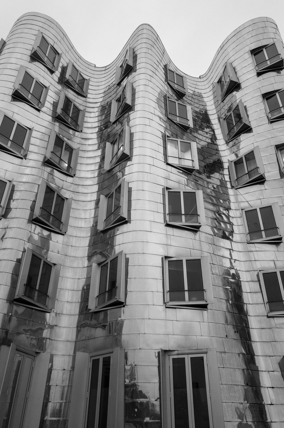 Undulating zinc facade forming successive waves, oblique windows, Düsseldorf